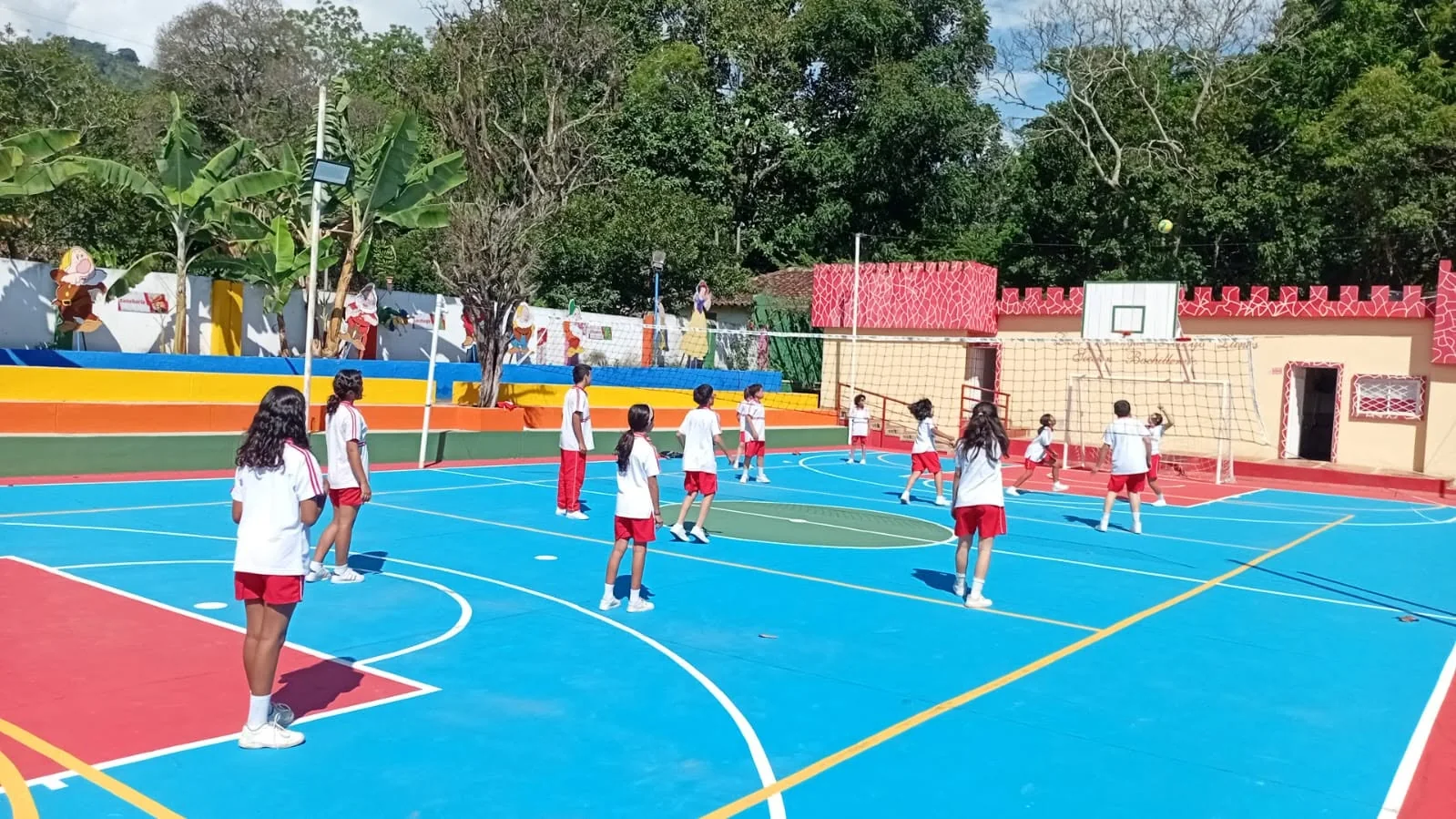 Actividad de estudiantes en la cancha azul y verde del colegio.