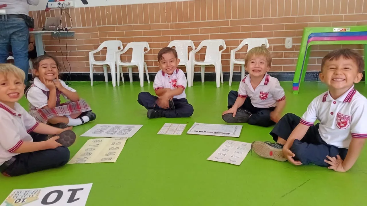 Niños pequeños exploran materiales de aprendizaje sobre césped sintético.